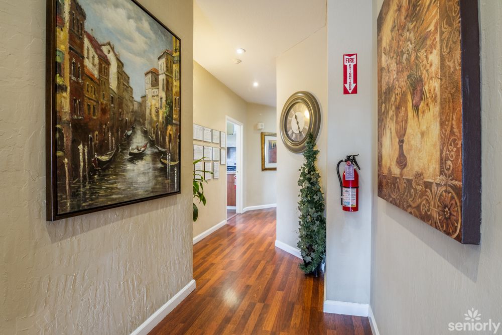 A well-decorated hallway featuring paintings, a fire extinguisher, and a wooden floor.