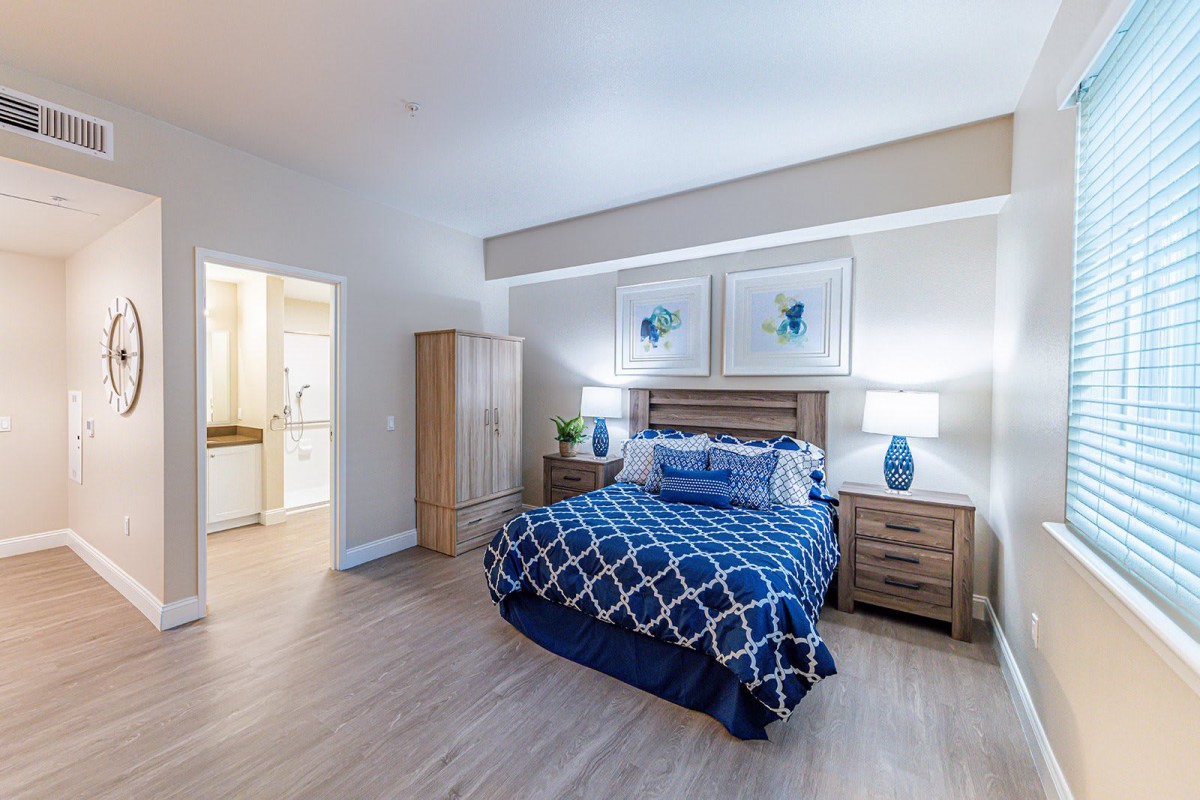A modern bedroom with a blue and white color scheme, featuring wooden furniture and stylish decor.