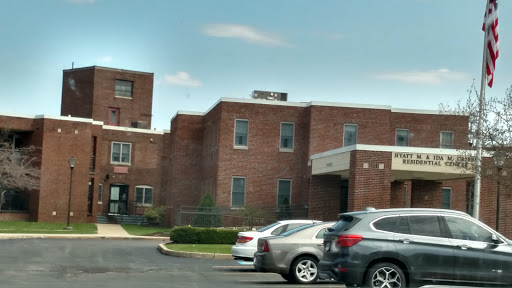 A brick building with a parking lot visible in front, set against a clear sky.