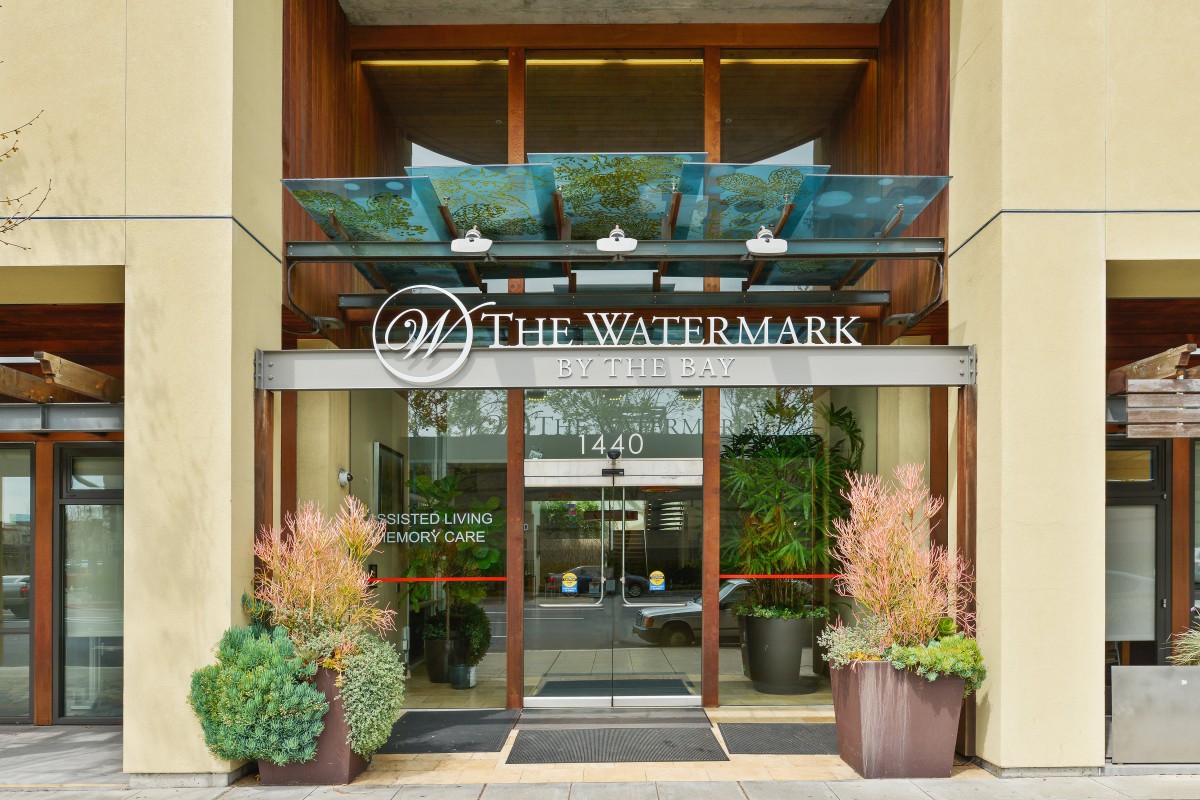 Entrance of The Watermark with glass doors and decorative plants.