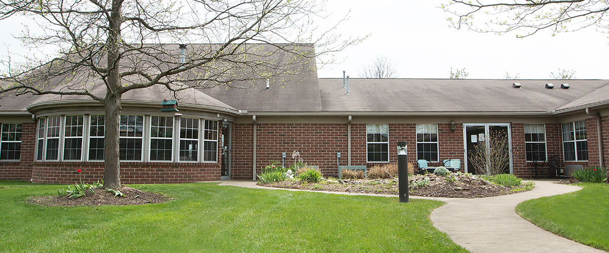 A brick house with a well-maintained lawn and garden in the front yard.