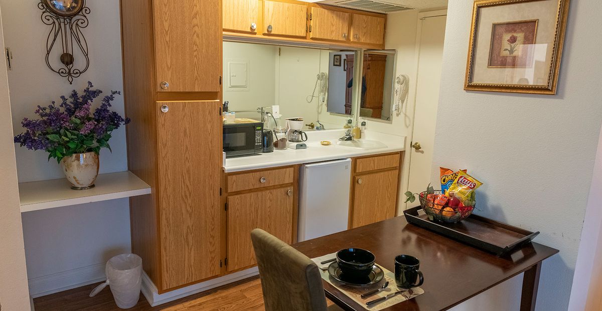 Cozy kitchen and dining area with wooden cabinets, a microwave, and a neatly set table.