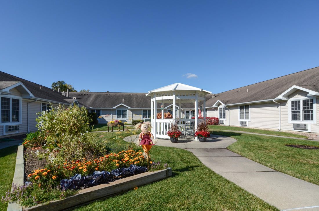 A beautiful garden with a gazebo surrounded by flowers and a pathway on a sunny day.