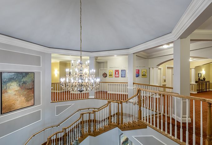 A grand staircase with a chandelier and wall artwork.