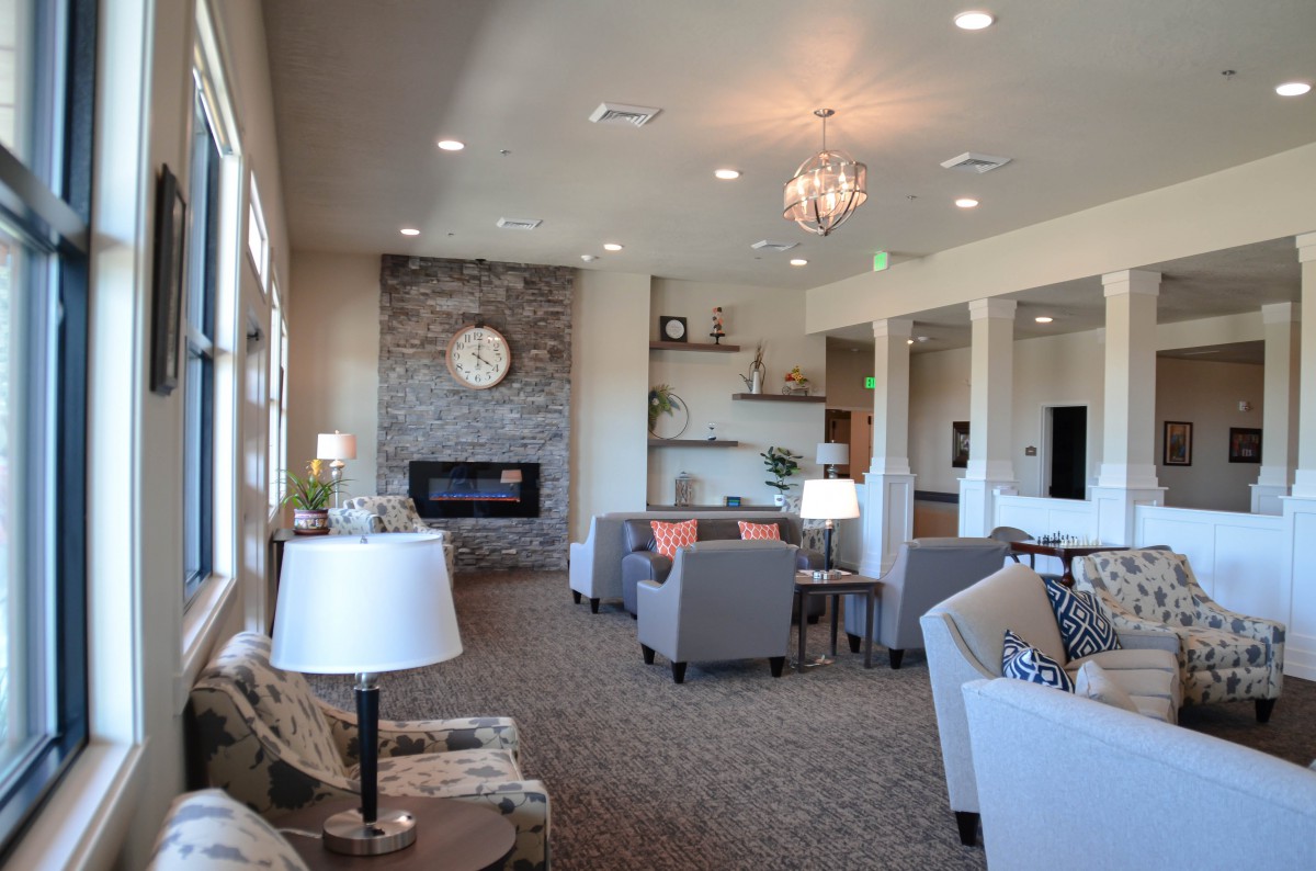 A modern living room with a fireplace, chandelier, and comfortable seating.