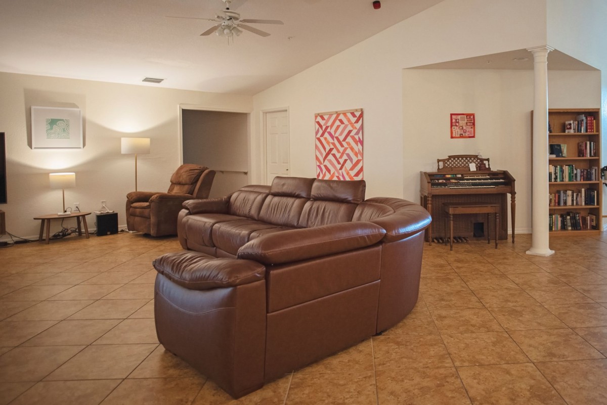 A cozy living room with a large brown leather sofa and a piano.
