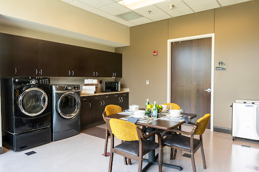 A contemporary kitchen and laundry area featuring a dining table with four chairs, modern appliances, and stylish decor.