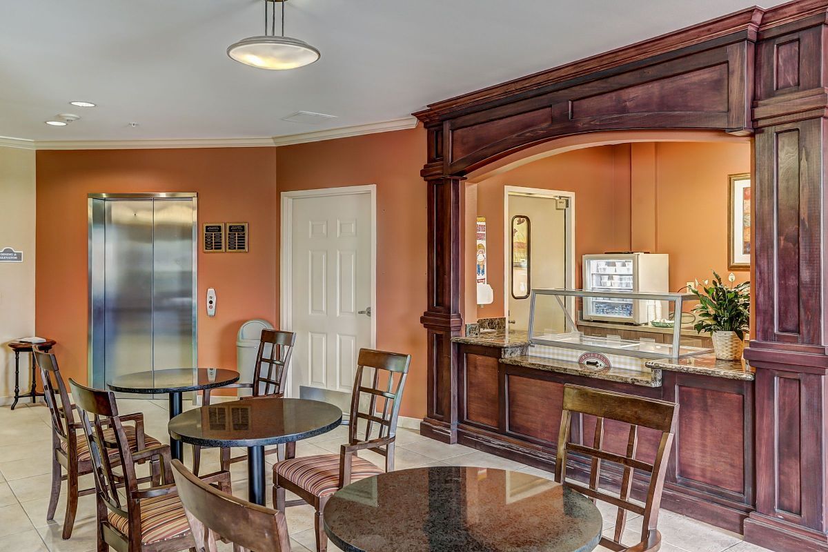 A cozy dining area with wooden tables and chairs, featuring a counter and an elevator nearby.