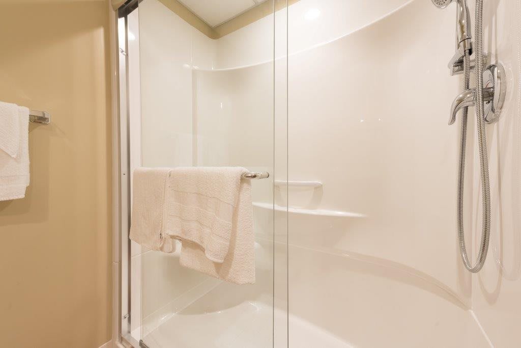 A modern shower with a glass door and towel hanging.