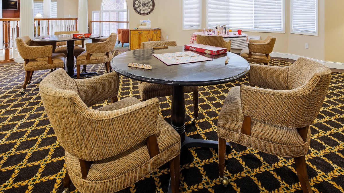 A cozy room with a round table surrounded by chairs and a patterned carpet.