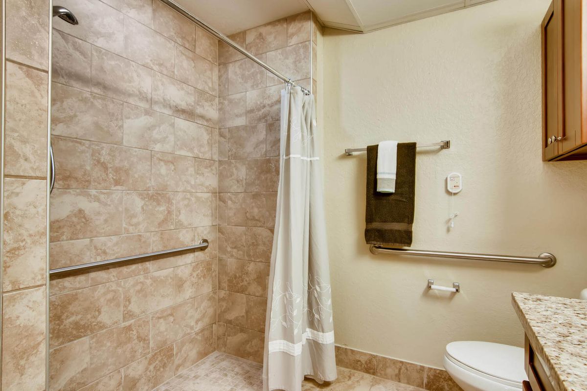 A neatly tiled bathroom with a shower area, curtain, mounted towels, and toilet.