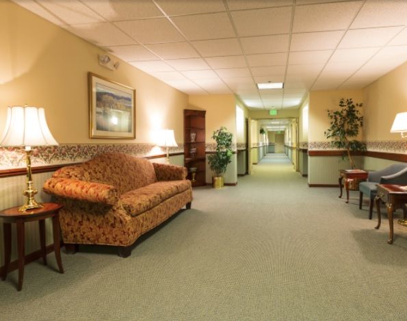 A well-lit hallway with a patterned sofa and various pieces of furniture.