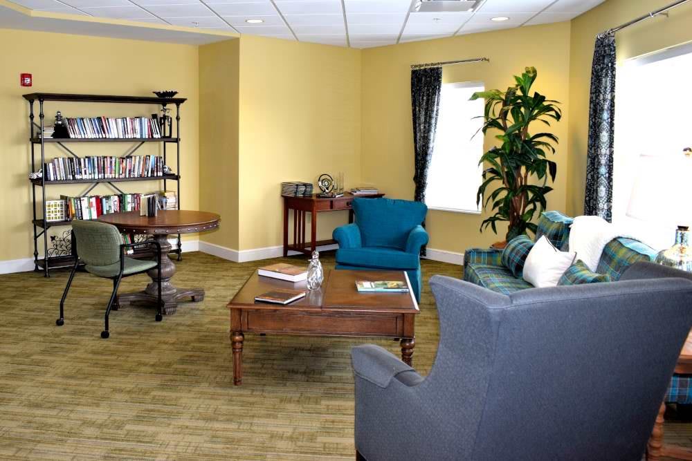 A cozy waiting room with comfortable seating, a coffee table, and a bookshelf.
