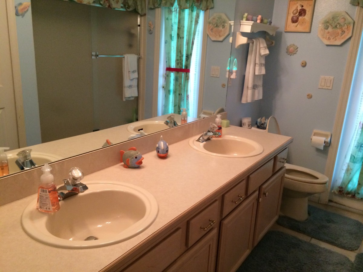 A bathroom with a double sink vanity, large mirror, and shower area.