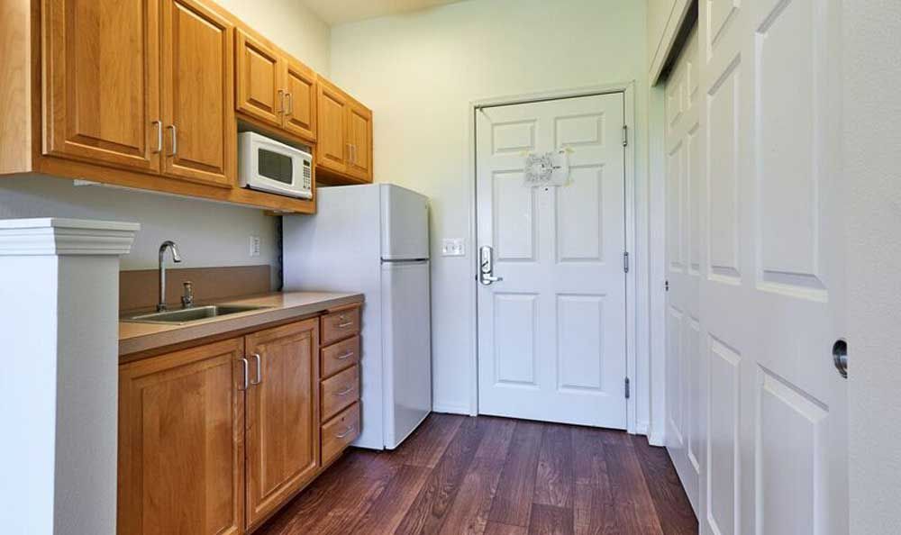 A small kitchen with wooden cabinets, a microwave, and a refrigerator.