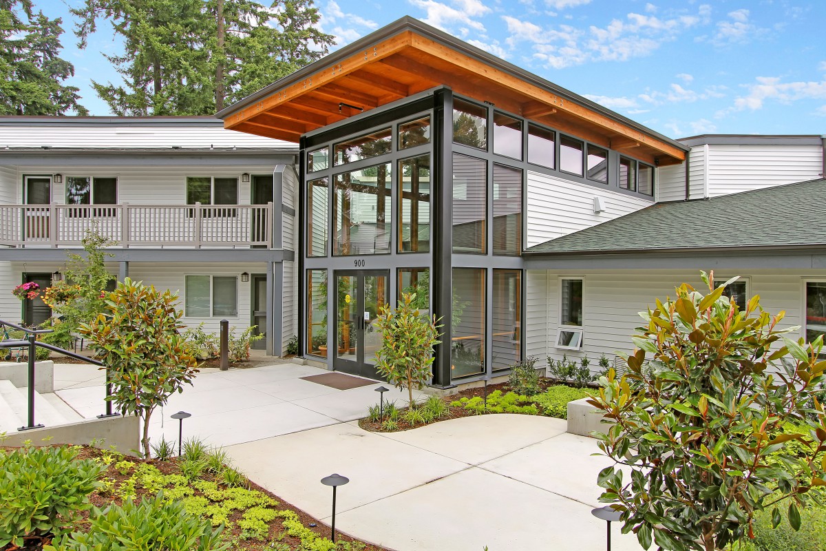A modern building with a glass facade and landscaped entrance.