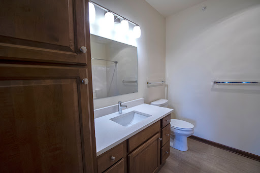 A clean and simple bathroom featuring a modern sink, wooden cabinetry, and a well-lit mirror.