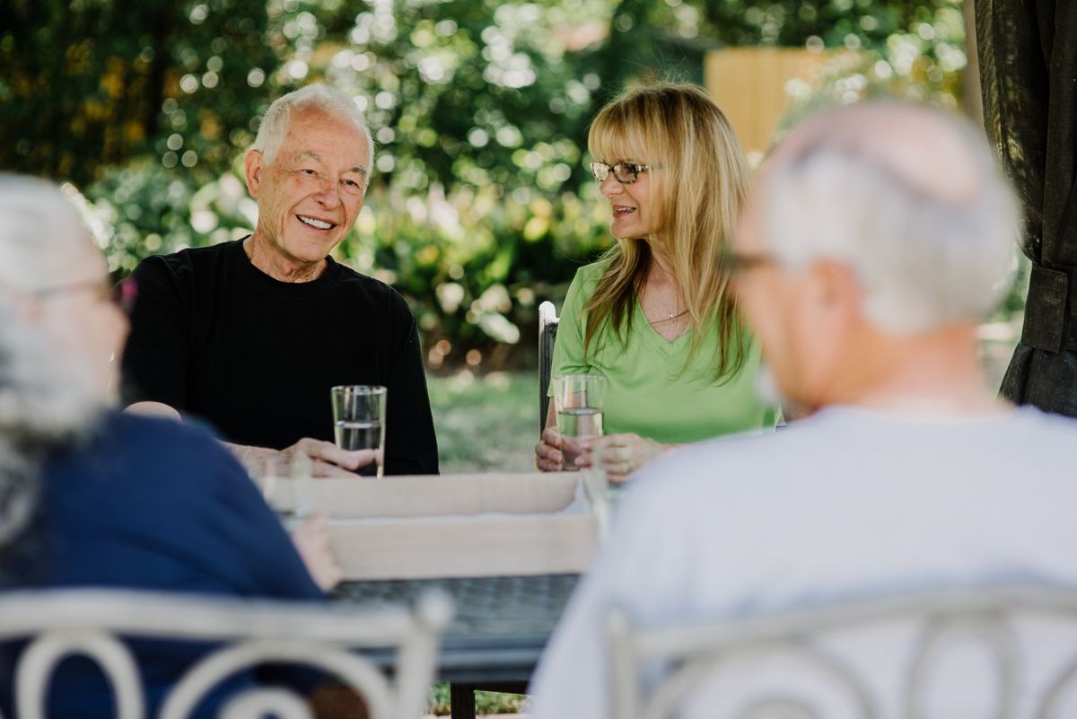A group of people enjoying a conversation in a garden setting while having drinks.