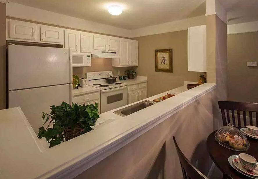 A cozy kitchen with white cabinetry and modern appliances, featuring an adjacent dining area.