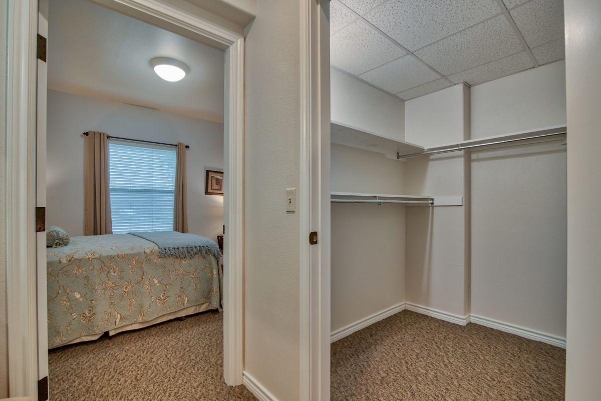 A view of a bedroom and an adjacent walk-in closet in a residential setting.