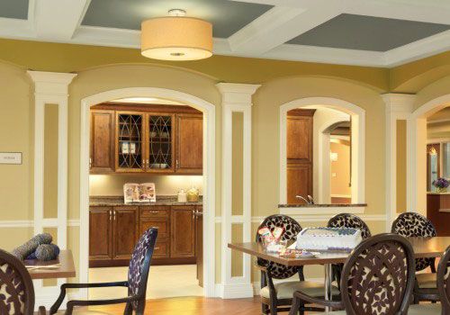 A cozy dining space with wooden cabinets and arched openings, featuring warm yellow walls and a modern ceiling light.
