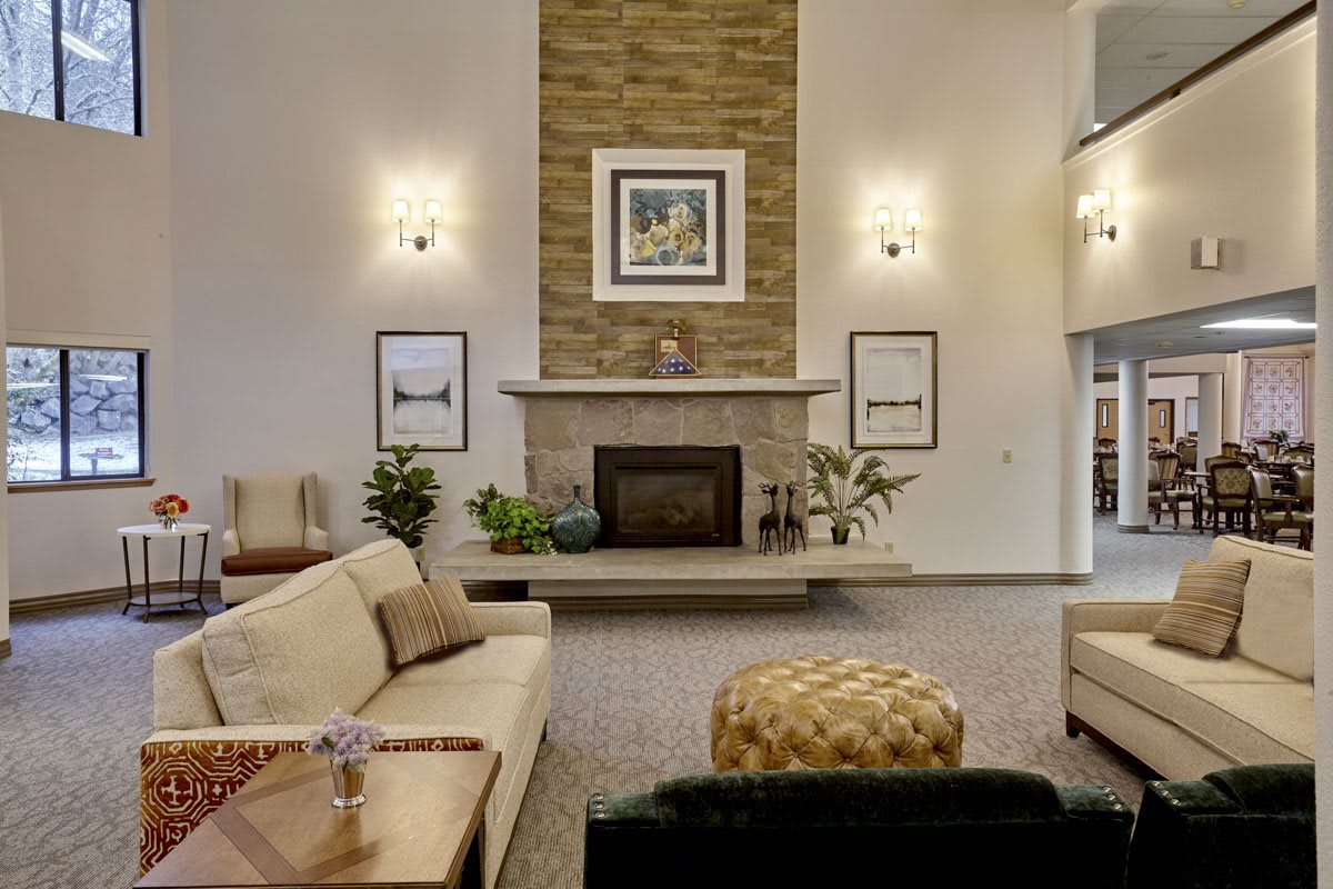 A cozy living room featuring a central fireplace with surrounding artwork and comfortable sofas.