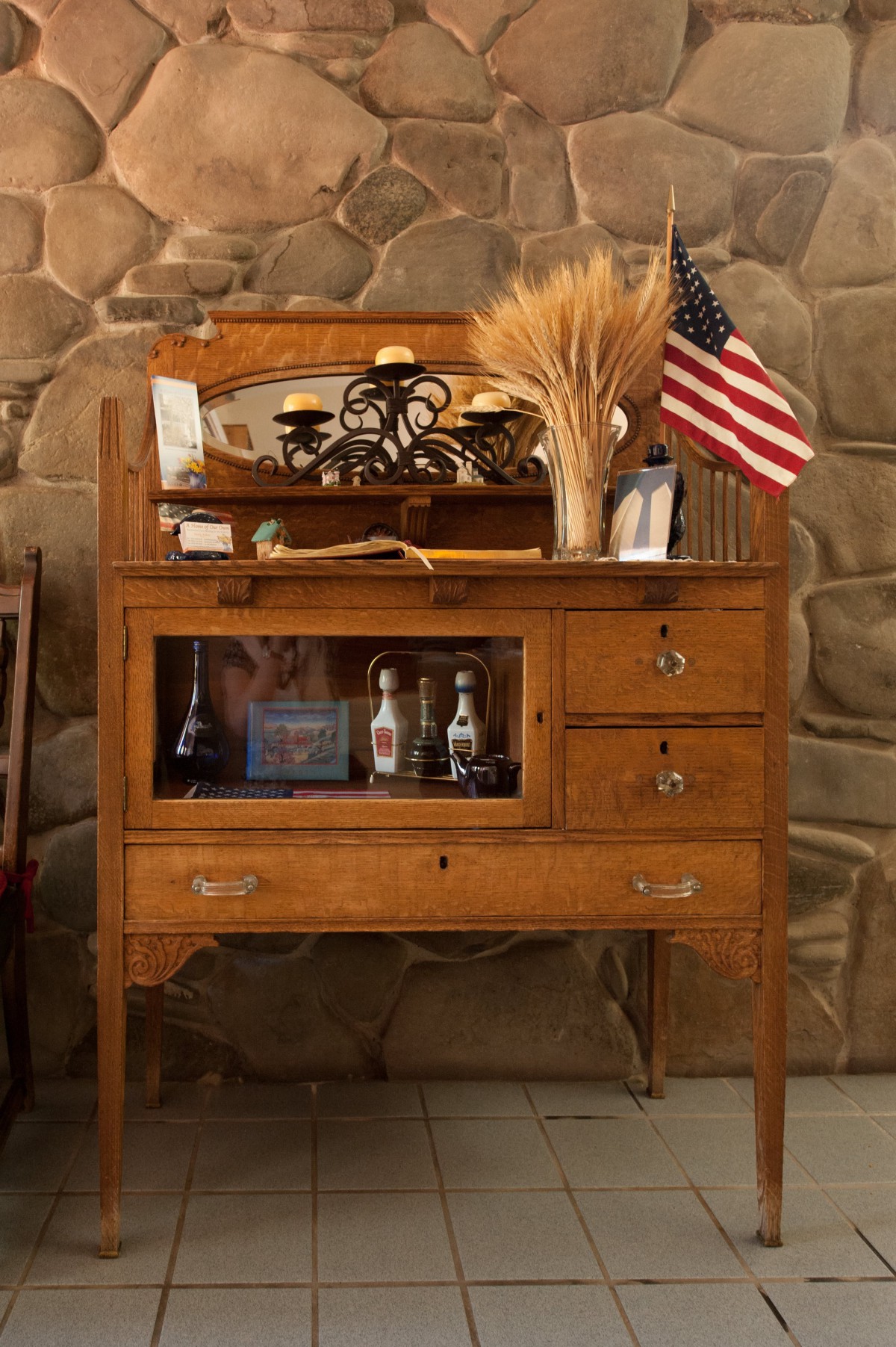 A vintage wooden cabinet adorned with decorative wheat stalks and a small American flag.
