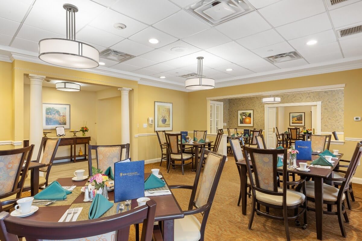 A well-lit dining area with neatly arranged tables and chairs, featuring elegant decor and menus on the tables.
