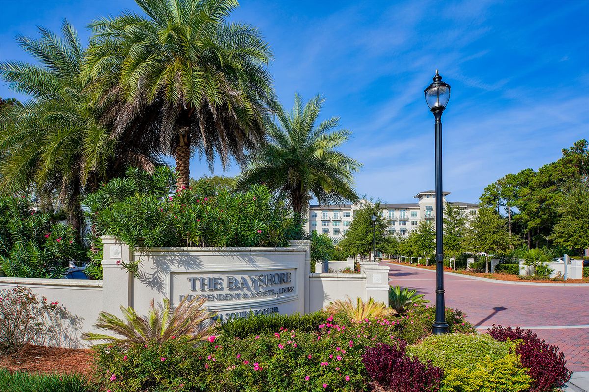 A well-landscaped residential area with palm trees and a sign displaying 'The Saxony.'