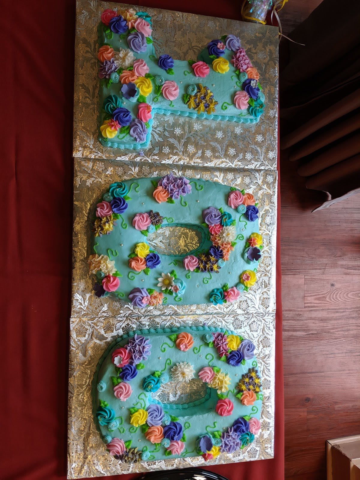 A festive, decorated cake in the shape of the number 100 with colorful flowers for a celebration.