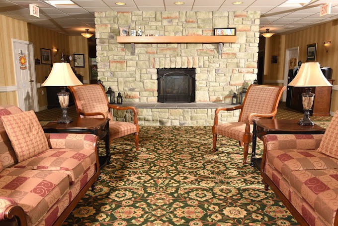 A cozy living room featuring a stone fireplace, armchairs, and a patterned rug.