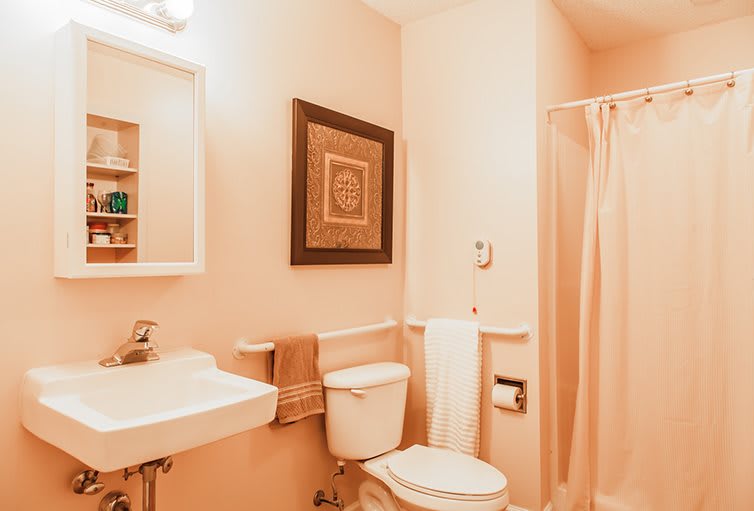 A cozy bathroom featuring a sink, toilet, and shower with warm lighting and decorative wall art.
