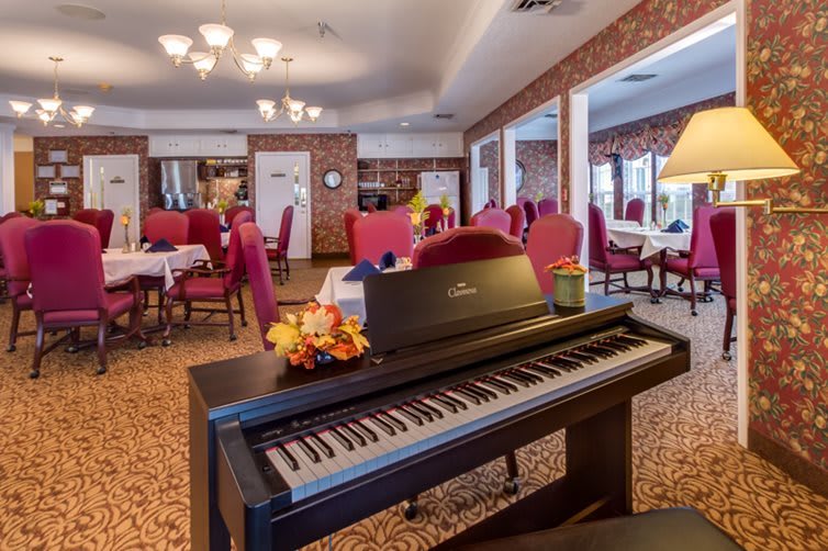 A cozy dining room with a digital piano and elegant red chairs.