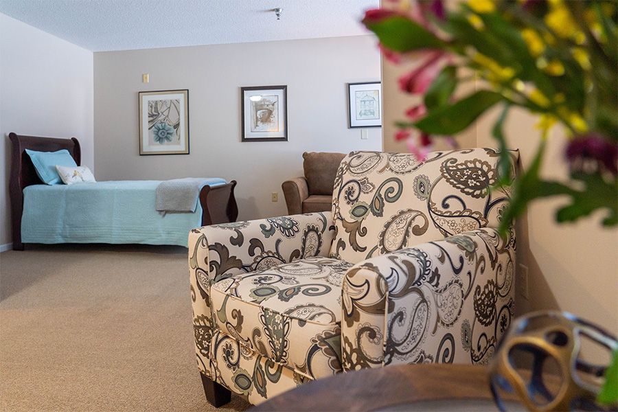 A cozy living room with a patterned armchair and floral decorations.
