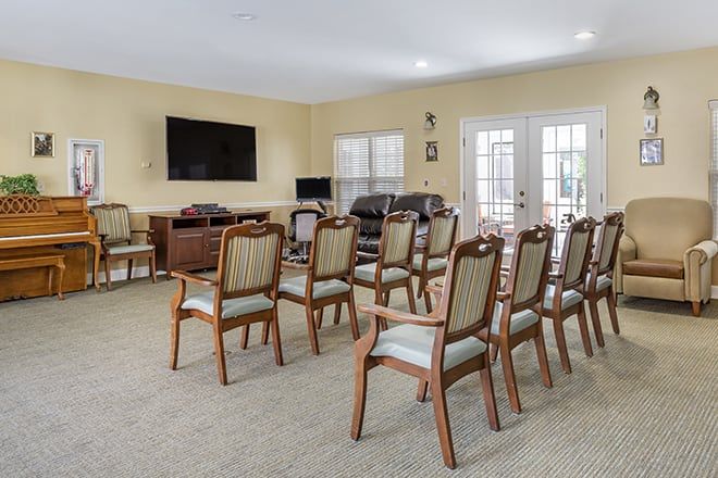 A well-arranged meeting room with rows of chairs facing a large television on the wall.