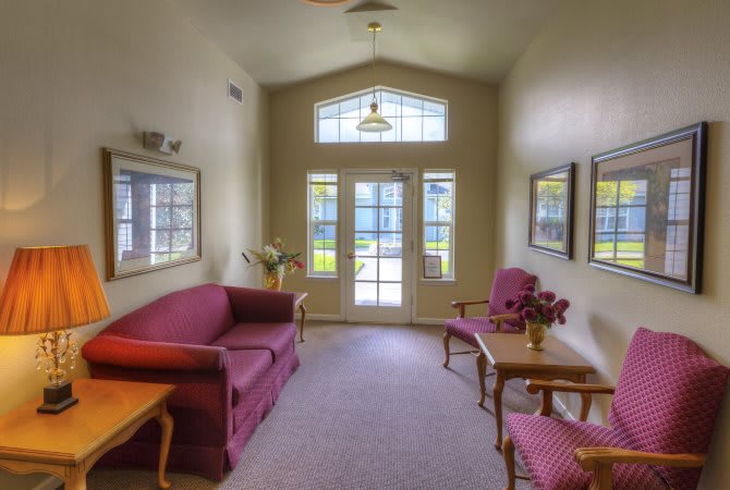 A cozy living room with natural light, featuring a sofa, chairs, and a table.