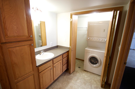 A spacious bathroom featuring a laundry area, complete with a vanity, sink, and washing machine.