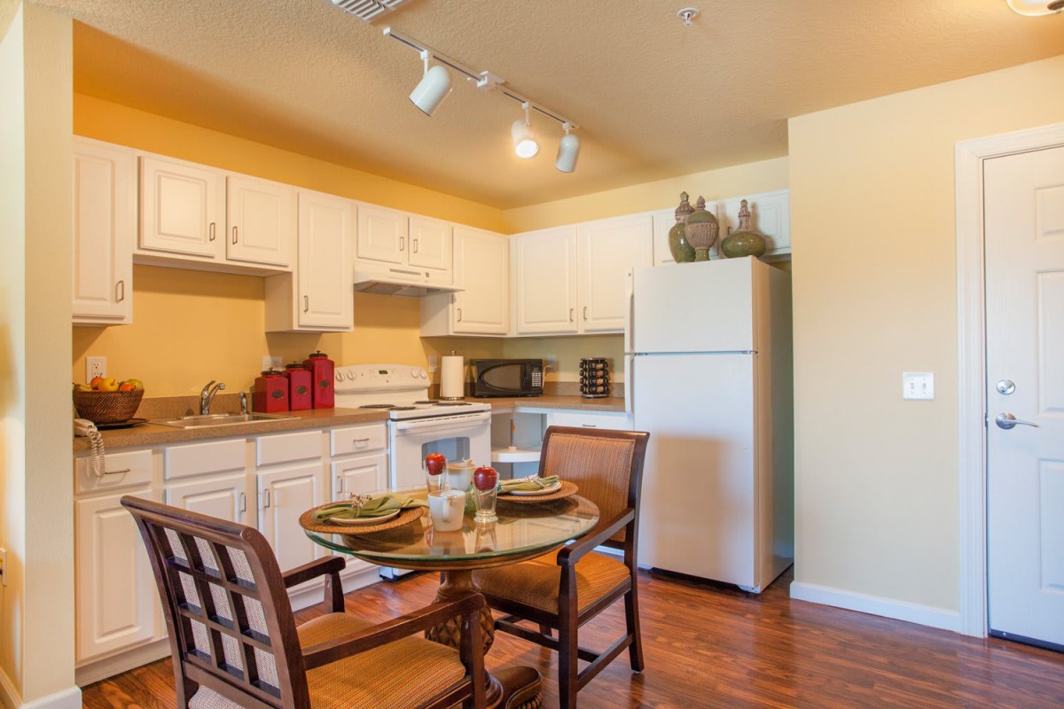 A cozy kitchen and dining area featuring a round wooden table with chairs, white cabinets, and essential appliances.