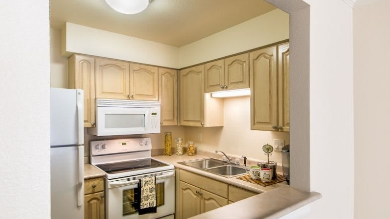 A cozy kitchen with wooden cabinets, featuring a microwave, oven, and sink.