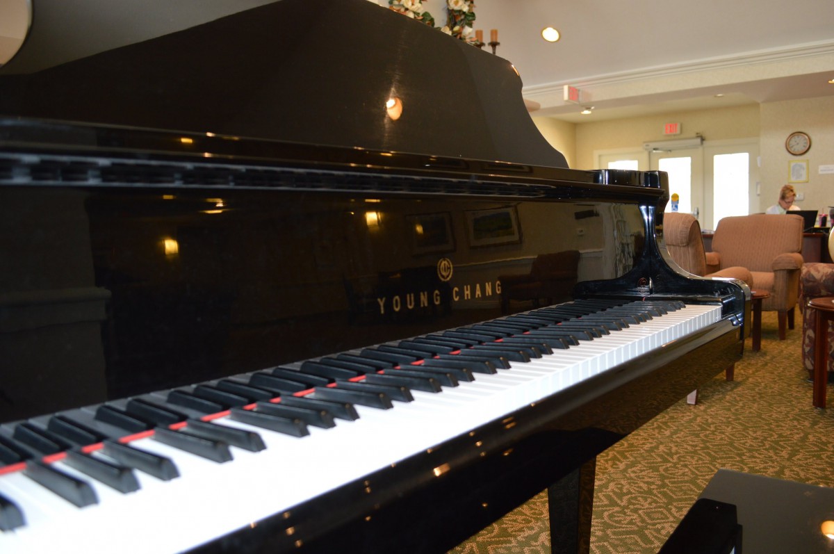 A black grand piano with a glossy finish in a well-lit room.