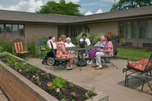 A group of senior citizens enjoying a sunny afternoon together in a garden setting.