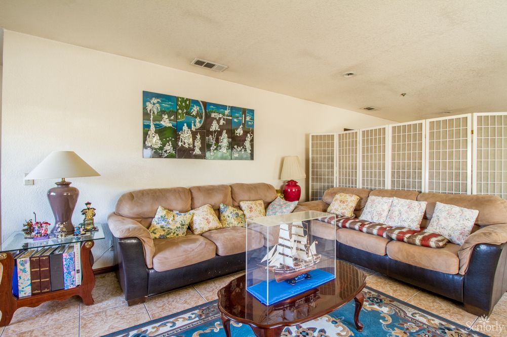 A cozy living room with a large couch and vibrant artwork, featuring a decorative ship model on the coffee table.