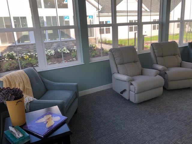 A cozy living room with recliners and a blue armchair near large windows.
