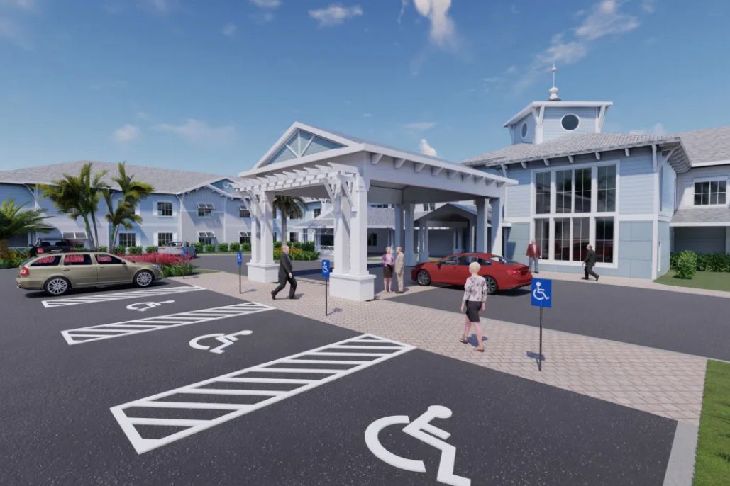 A building with a covered entrance, surrounded by a parking lot with accessible parking spots and several people walking nearby.