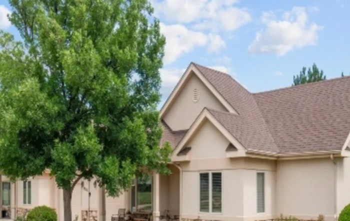 A modern suburban house with a gabled roof and a tree in the front yard.