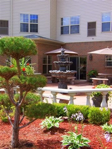 A peaceful garden patio with a central fountain and surrounding greenery.