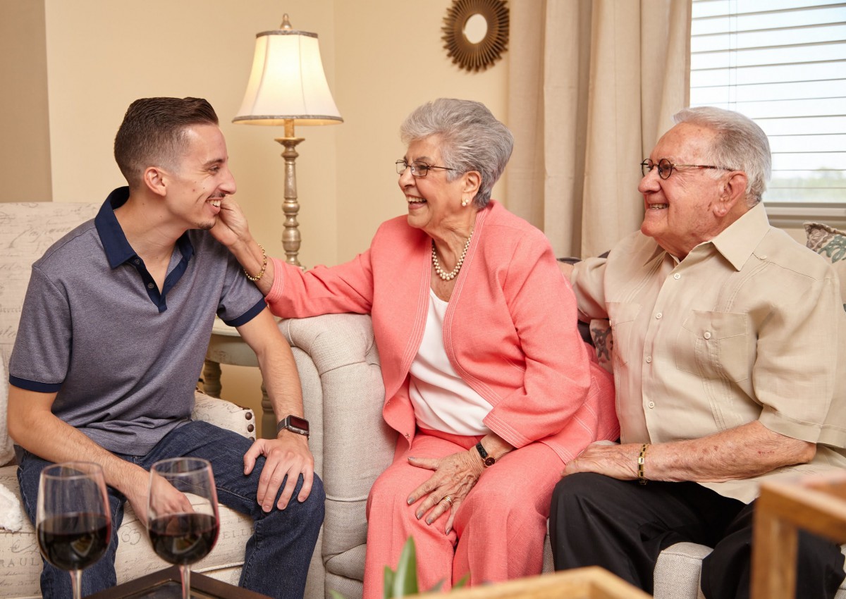 A young man shares a happy moment with his grandparents in the living room.