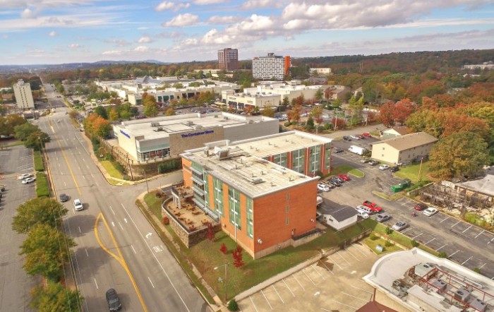 Aerial view of an urban area with buildings, roads, and a cloudy sky.