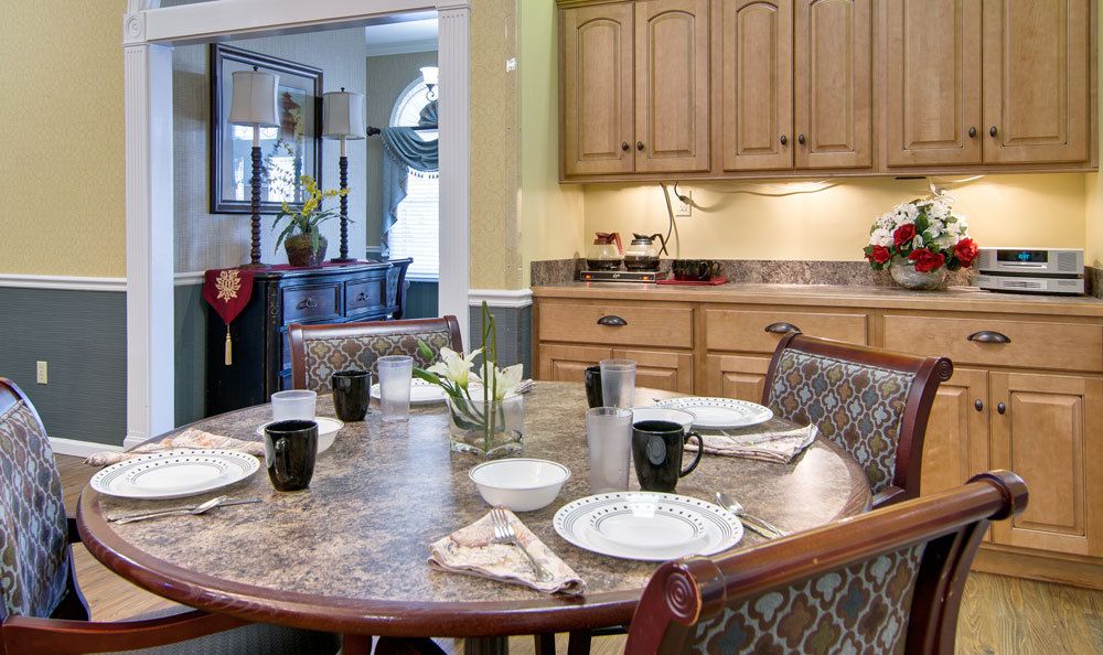A cozy dining area with a table set for a meal, featuring wooden cabinets and warm lighting.