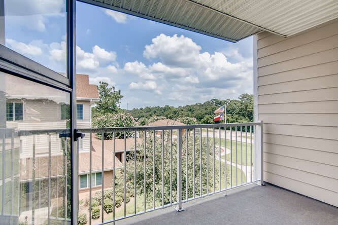 A residential balcony with a view of surrounding buildings and a partly cloudy sky.